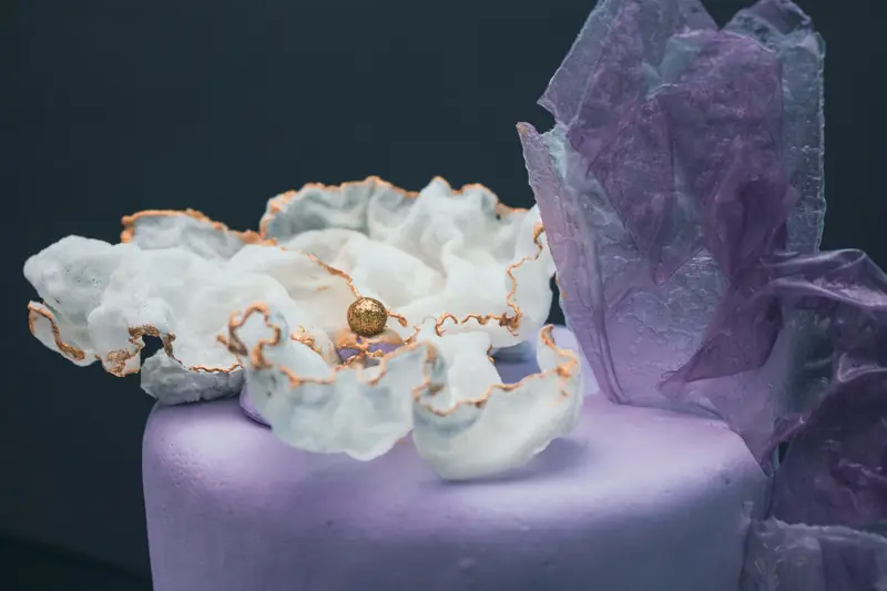 A delicate cake adorned with edible flowers and crystals, featuring intricate design