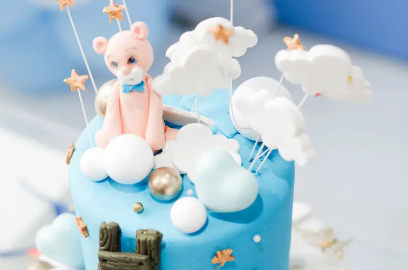 Charming cake decorated with blue fondant, teddy bear, clouds, and star accents, perfect for a children's party