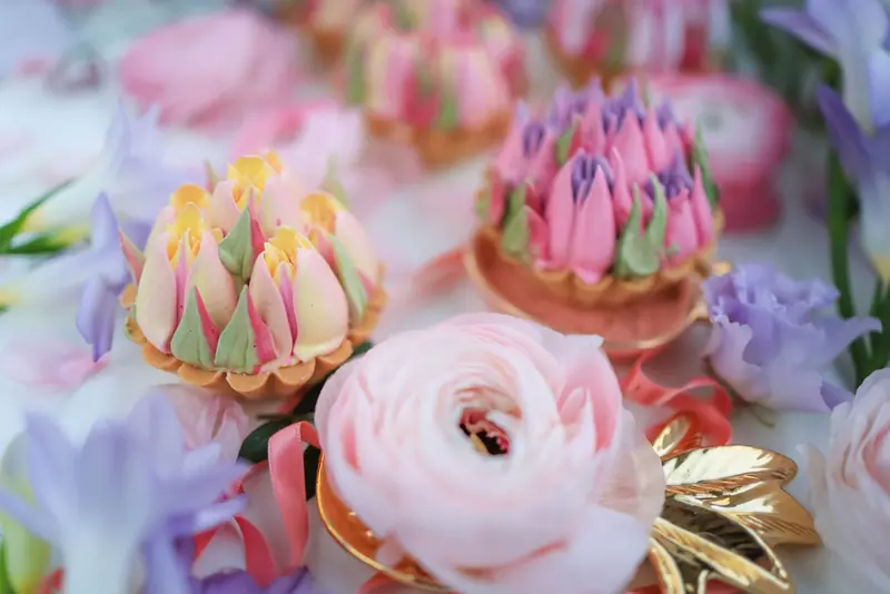Elegant floral cupcakes with intricate icing surrounded by fresh flowers