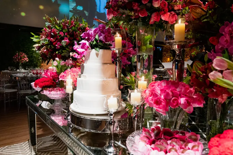 A beautifully decorated wedding reception table with a tiered cake and vibrant floral arrangements