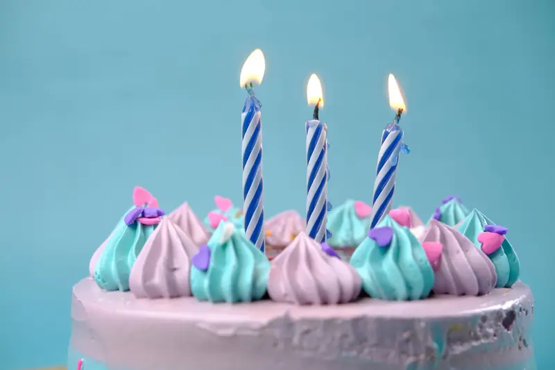 A vibrant birthday cake with pastel icing and lit candles, perfect for celebrations